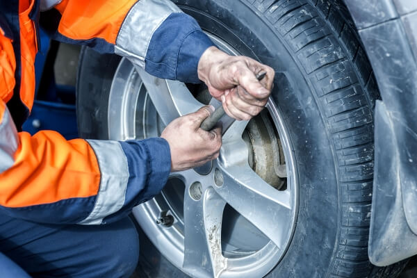 Mechanic installing new tyres on a car wheel in a garage