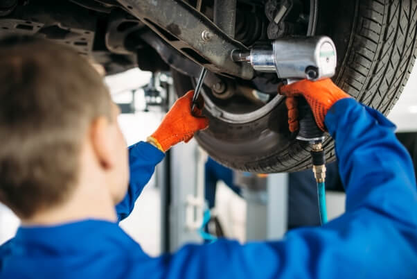Technician with a wrench repair car suspension