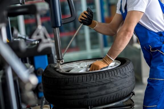 Mechanic balancing car wheel on balancer. Concept of wheel alignment and tyre sevrices.